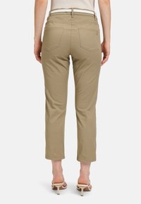 Beige cropped broeken met een gladde textuur, twee achterzakken en een zichtbaar merklogo. Gecombineerd met beige hakken.