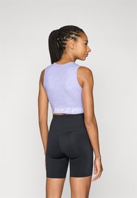 Purple Nike Pro crop top with a textured design, featuring a logo band. Paired with high-waisted black shorts, smooth fabric, and fitted shape.