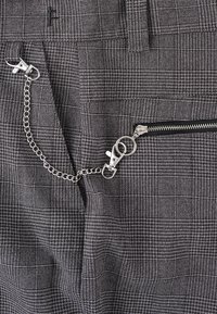 Gray patterned fabric with a textured surface; includes a side zipper with a silver chain and clasp detail.