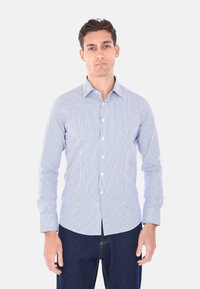Camicia button-up a righe blu chiaro e bianche con maniche lunghe, colletto classico e vestibilità slim. Il tessuto è liscio con una consistenza asciutta.
