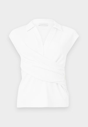 Λευκό αμάνικο μπλουζάκι με λεπτομέρεια τύλιγματος, γιακά στη λαιμόκοψη και σφηκοειδές γύρισμα στη μέση σε απλό φόντο.