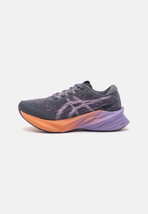 Chaussure de course gris foncé et lavande avec semelle intermédiaire orange et talon violet, présentant le logo de la marque et un design en tricot sur la tige.
