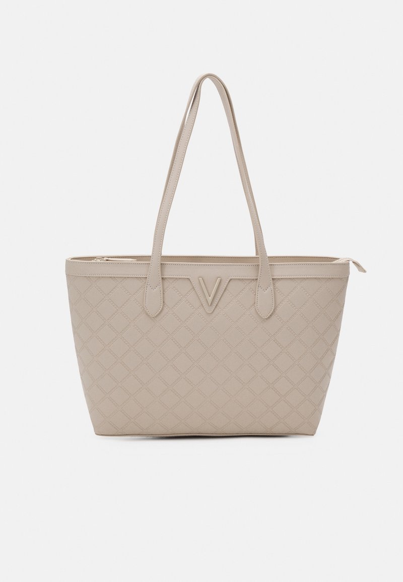Beige tote bag with quilted pattern, dual handles, V-shaped accent on front, and top zipper closure. Smooth texture. Rectangular shape.