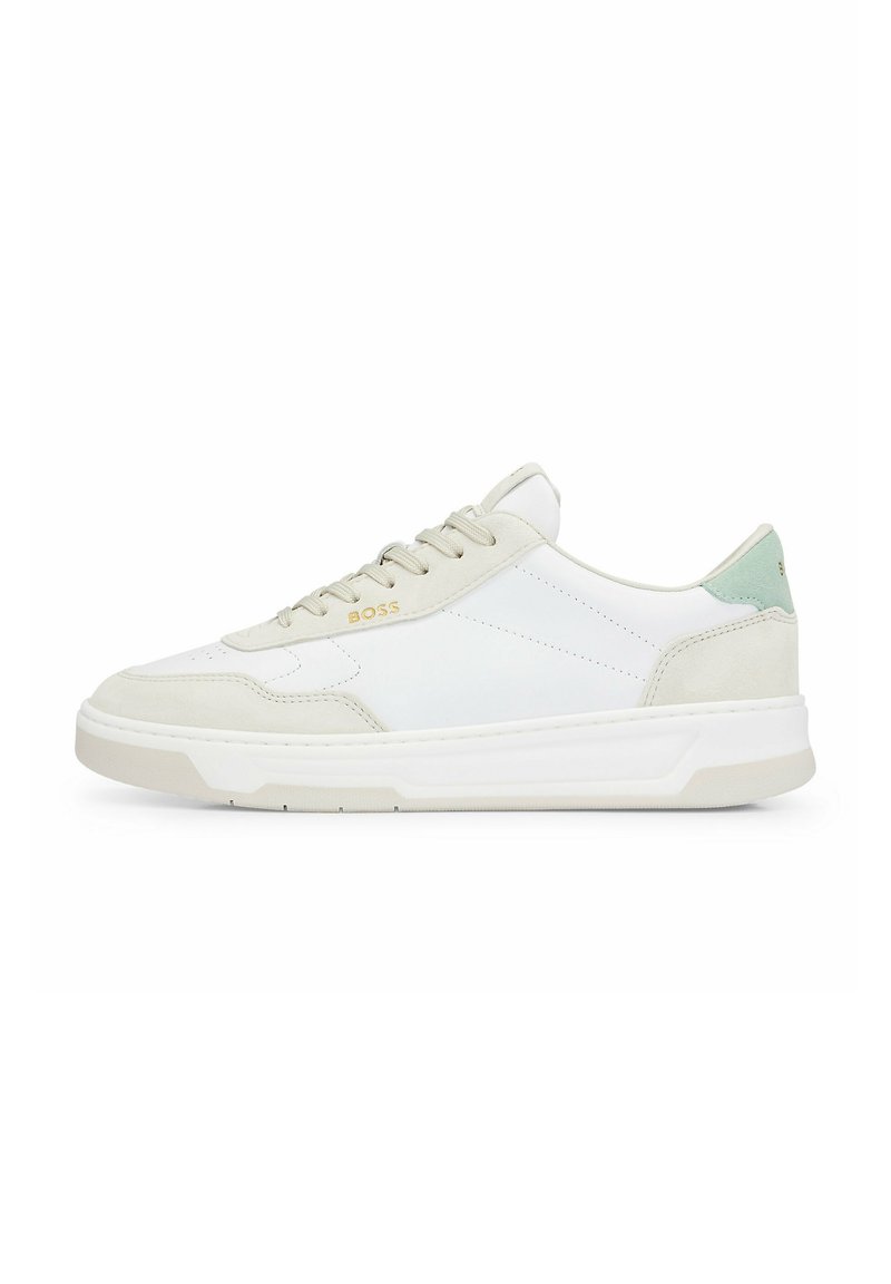 Weiße Leder-Sneaker mit beigen Wildlederelementen, die ein strukturiertes Design, flache Schnüre und einen grünen Fersenpatch aufweisen. Goldenes Logo an der Seite.