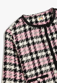 Zwart, wit en roze houndstooth-patroon cardigan met textuurstof, ronde halslijn en decoratieve knopen.