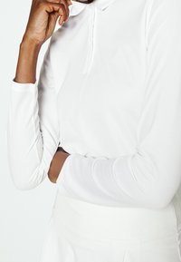 Polo shirt bianco a maniche lunghe con colletto a botton-down, texture liscia, design aderente e silhouette affusolata.