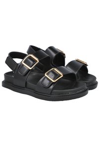 Sandalias de cuero negro con dos correas anchas, detalles en hebilla dorada y una suela de goma plana. Diseño con talón abierto y textura suave.
