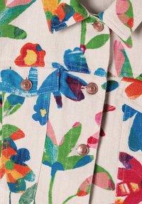 Jeansjack met bloemenpatroon, gekenmerkt door veelkleurige bloemen op een lichte achtergrond, met koperen metalen knopen en gestikte accenten.