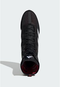 Black high-top athletic shoe with a textured knit upper, featuring white stripes, red accents, and black laces. Interior has a plaid pattern.