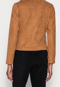 Veste en daim marron avec un design ajusté, dotée de manches longues et d'une coupe mi-longue. Texture lisse et pas de détails en métal visibles.
