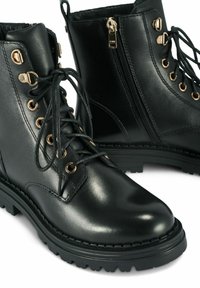 Czarne skórzane botki za kostkę z złotymi detalami, sznurówki z przodu, zamek błyskawiczny z boku, teksturowana gumowa podeszwa oraz wzmocnione przeszycia.