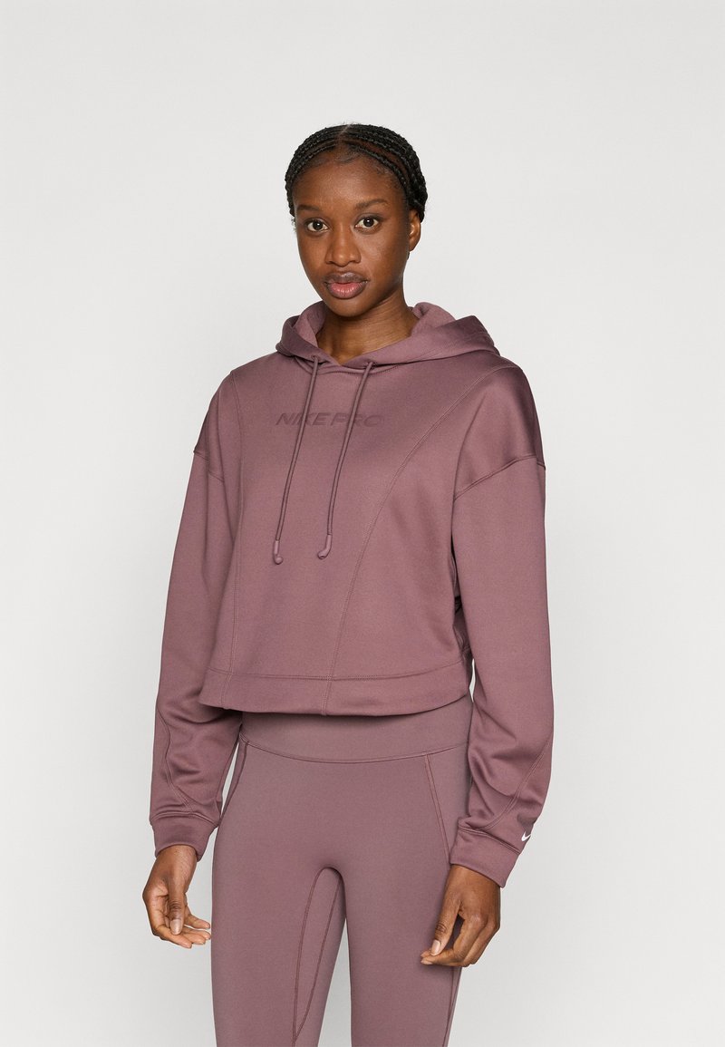 Afgekorte capuchontrui in mauve met het "Nike Pro" logo, voorzien van een capuchon met trekkoord en geribbelde boorden. Gecombineerd met bijpassende legging.