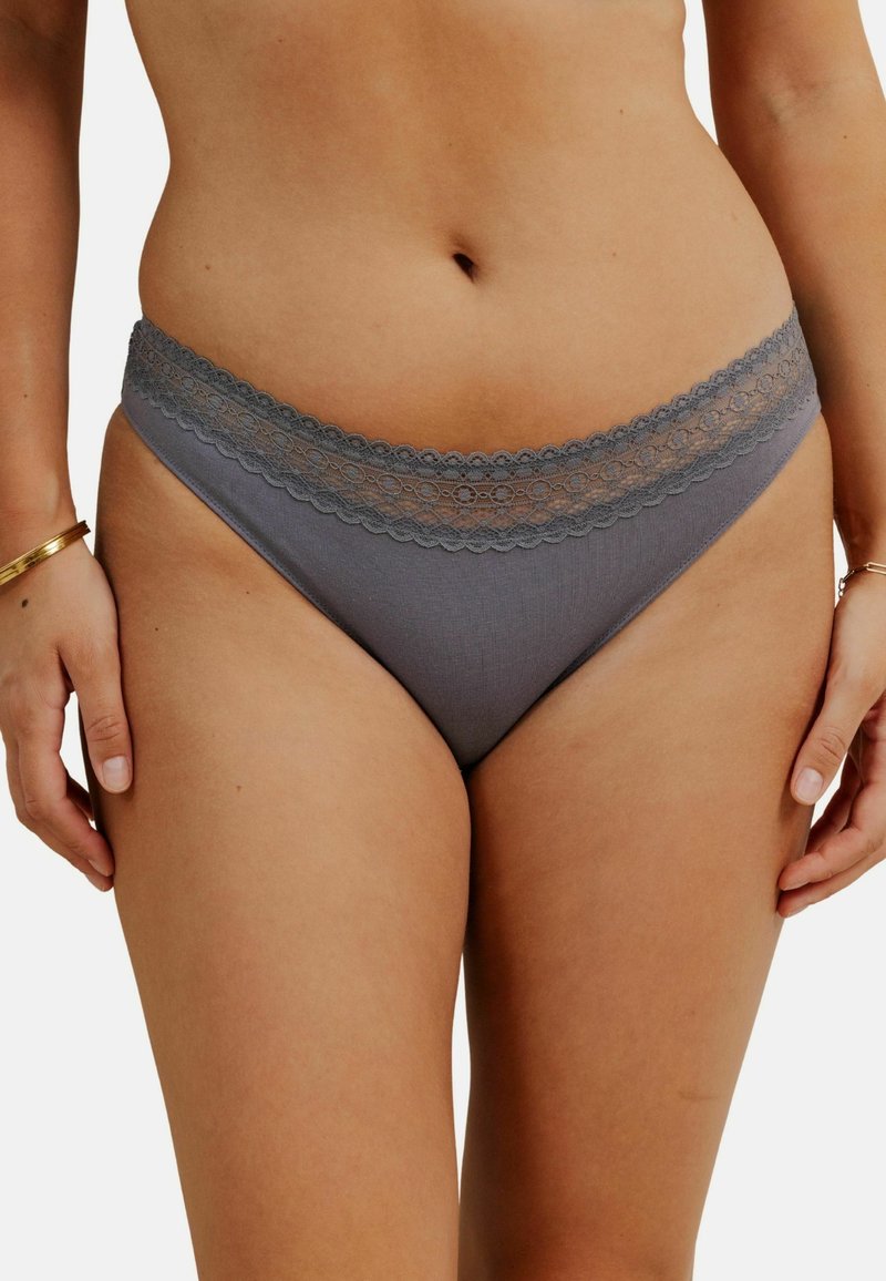 Slip gris avec une bordure en dentelle à la taille, fabriqué à partir d'un matériau lisse avec une texture douce et des détails de conception minimalistes.