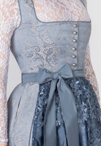Blaues und beigefarbenes Kleid mit beeindruckender Spitzen- und Blumenmusterung, silbernen Knöpfen, einer Satinschleife in der Taille und geschichteten Texturen.