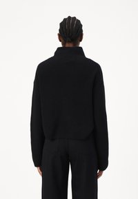 Maglione nero a maglia con collo alto, spalle cadenti e texture a coste, caratterizzato da una lunghezza cropped e una vestibilità morbida.