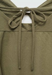 Sweat à capuche vert kaki avec une fermeture à nouer au niveau du cou, en tissu doux et texturé, avec un détail découpé dans le dos.