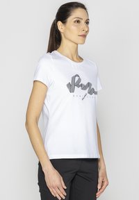 Biała bawełniana koszulka z krótkim rękawem, z luźnym krojem oraz czarnym paskowanym nadrukiem, na którym widnieje napis "PAM".