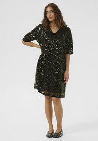 Fekete flitteres ruha rövid ujjal és V-nyakkivágással. Csillogó részletekkel és laza sziluettel rendelkezik, melynek szegélye éppen térd felett található.