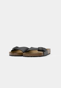 Melni slip-on sandalīši ar platu siksnu un regulējamu sprādzi, aprīkoti ar korķa zolīti un teksturētu gumijas zoli, kas nodrošina saķeri.