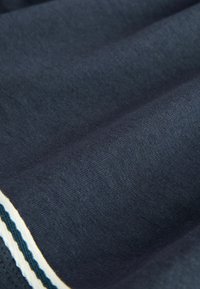 Tela azul oscuro con una textura fina de punto y un borde a rayas blanco y verde azulado a lo largo de un lado.