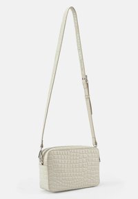 Bolso bandolera blanco con estampado de cocodrilo, forma rectangular, correa ajustable y cierre con cremallera. Textura suave y herrajes pulidos.