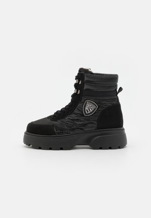 Bottes de combat noires avec tige en synthétique, design texturé, fermeture à lacets à l'avant, col rembourré et semelle épaisse et robuste. Présente un patch logo.