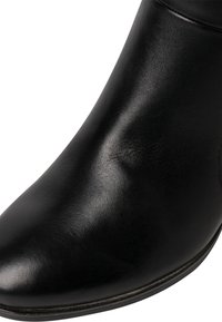 Botte en cuir noir lisse avec bout arrondi et bord visible de la semelle, vue en gros plan.