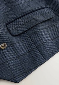 Blazer à motif écossais marine avec un col cranté, une fermeture à un bouton et une poche poitrine avec un détail cousu. Texture de tissu lisse.