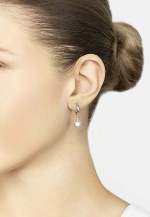 Ezüst karika fülbevalók napsugár mintával, középen egy fehér drágakővel, fényes felülettel és aprólékos kidolgozással.