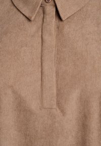 Brown corduroy shirt featuring vertical ribbed texture, pointed collar, and a half-button placket for closure.