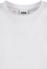 Biały t-shirt z okrągłym dekoltem, z wewnętrzną metką pokazującą "URBAN CLASSICS" oraz małą czerwoną metką ostrzegawczą z napisem "Keep away from fire."