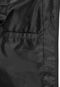 Musta, sileä kangas takin sisäpuolella, jossa on vaakasuora tasku, ommeltu samansävyisellä langalla, vetoketju oikealla puolella.