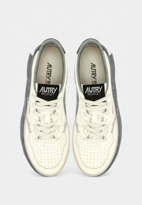 Sneakers in pelle bianca con accenti grigi, punta traforata, lacci piatti e etichetta nera sulla linguetta con il nome del marchio. Suola in gomma.