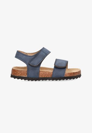 Sandalia de cuero azul con dos correas ajustables de Velcro, plantillas de corcho y suela de goma negra texturizada. La vista lateral muestra su diseño abierto.