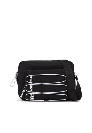 Črna torbica čez ramo z belimi elastičnimi vrvicami na sprednjem žepu in nastavljivim trakom, na katerem je vtisnjen napis "JEANS".