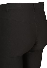 Czarne legginsy o gładkiej fakturze, wysokim stanie i dopasowanym kroju, z widocznymi detalami szwów oraz bezszwowym wykończeniem z tyłu.