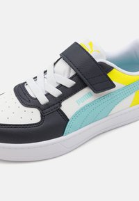 Puma sneaker met een marineblauwe en witte leren bovenkant, een elastische band, lichtblauwe accenten en een gele logo. Geperforeerde neus voor ademend vermogen.