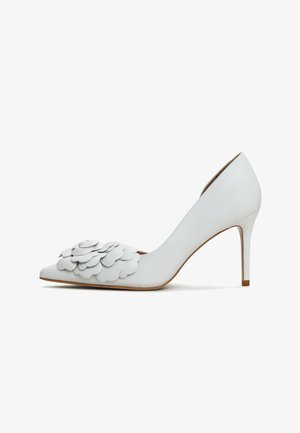 Białe skórzane szpilki z wydłużonym noskiem i warstwowym detalem w postaci aplikacji kwiatowych z przodu, z eleganckim obcasem typu stiletto.