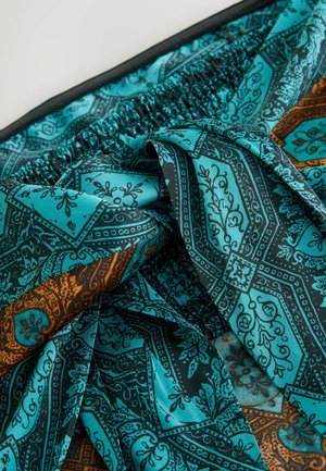 Türkiissinine mustriga kangas, millel on keerukad mustad ja oranžid motiivid, kogutud vöökoht ja sile tekstuur.