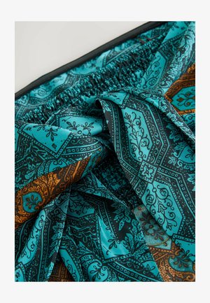 Türkiissinine mustriga kangas, millel on keerukad mustad ja oranžid motiivid, kogutud vöökoht ja sile tekstuur.