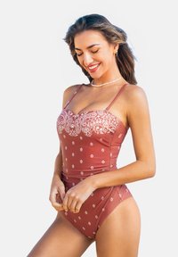 Einteiliger Badeanzug in staubigem Rosé mit weißem Blumenmuster. Verfügt über dünne, verstellbare Träger und eine figurbetonte Silhouette. Glatte Stofftextur.