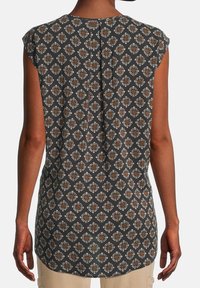 Mouwloze top met patroon in donkergrijs met een geometrisch ontwerp in wit en bruin. Heeft een split aan de achterkant en een gladde textuur.