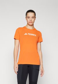 Oranžna kratka majica z lahkim materialom in okroglim izrezom, ki ima čez prsni del belo "TERREX" logo.