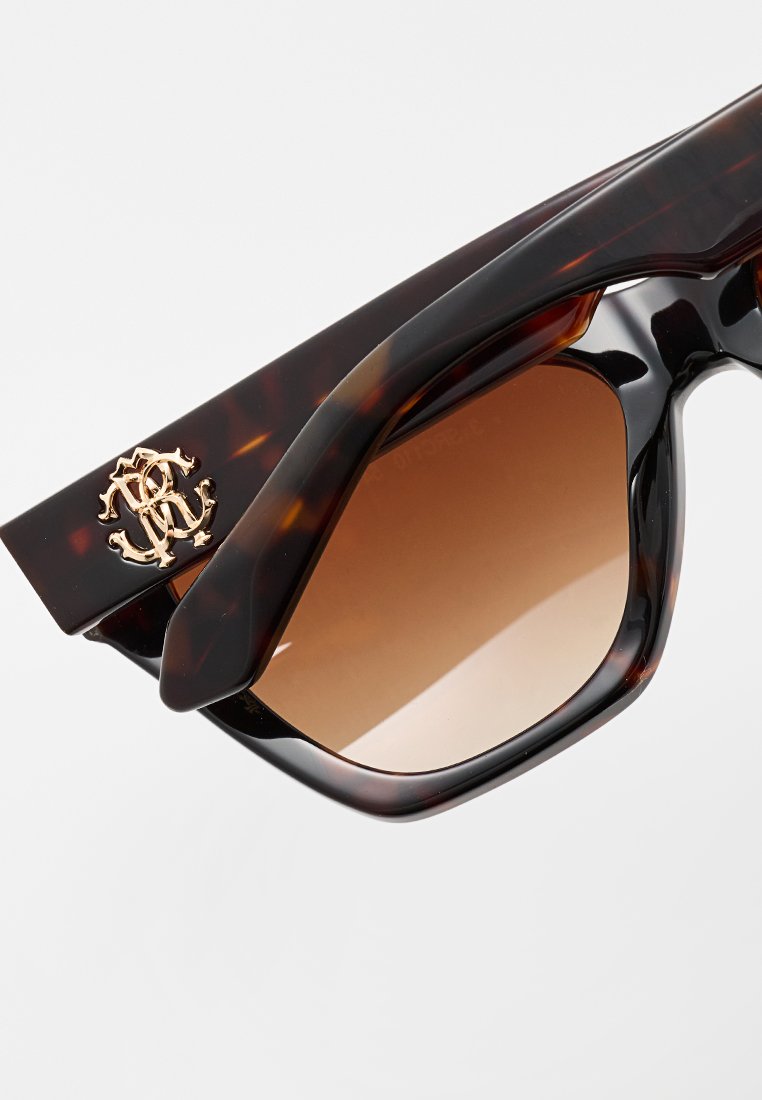 Lunettes de soleil écaille avec verres dégradés marron. Présente un logo doré sur la branche et une monture épaisse et angulaire.