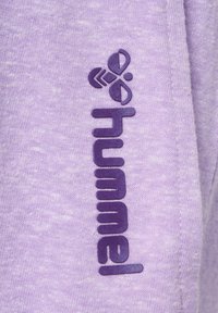 Logo violet "hummel" et emblème d'abeille stylisé imprimés verticalement sur un tissu violet clair texturé.