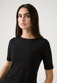 Schwarzes Kurzarmoberteil aus glattem Stoff, mit rundem Ausschnitt und taillierter Silhouette. Schlichtes Design mit klaren Linien.