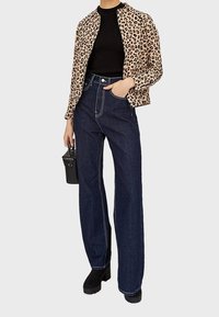 Giacca leopardata, top nero a costine, jeans scuri a vita alta, stivaletti platform neri e una piccola borsa nera con borchie.