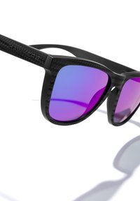 Ochelari de soare negri cu un cadru texturat din fibră de carbon, design unghiular și lentile miroir mov. Include logo-ul brandului gravat pe tâmple.