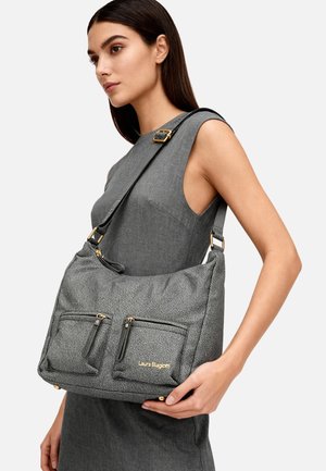 Donna che indossa un abito grigio senza maniche e tiene una borsa grigia con texture, due tasche anteriori con zip e dettagli in oro sulla spalla.