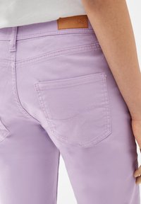 Lilac denim jeans with a smooth texture, featuring a back pocket and a brown leather patch labeled "QS."